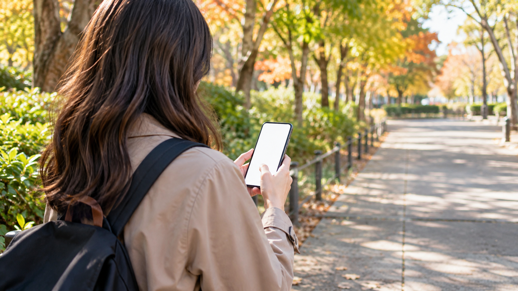 秋の屋外でスマートフォンの予定を確認する来園者の後ろ姿