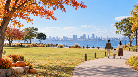 秋の海辺の芝生公園を歩く家族の後ろ姿と控えめなハロウィーン装飾のイメージ